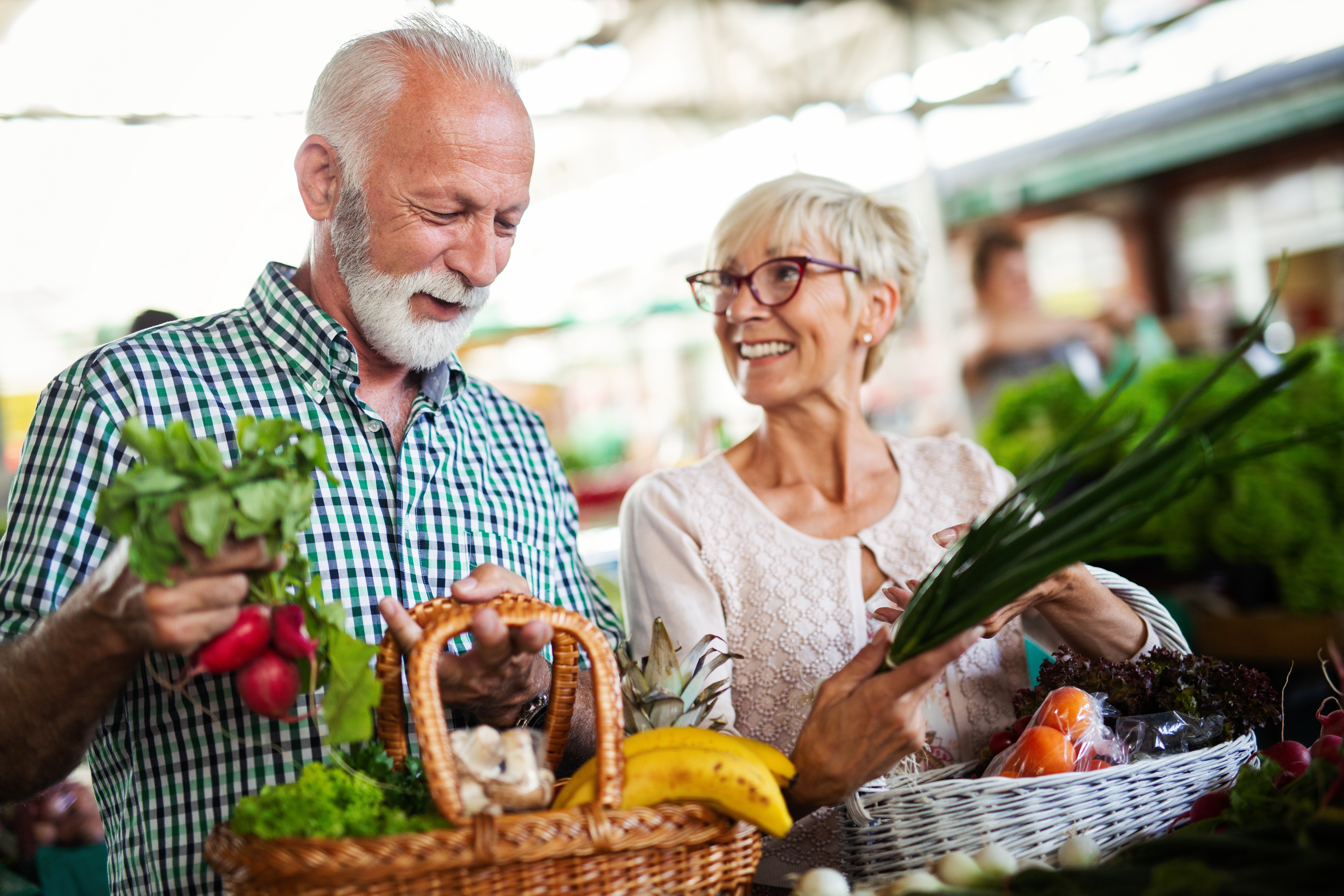 seniors laughing with basket of fresh food 