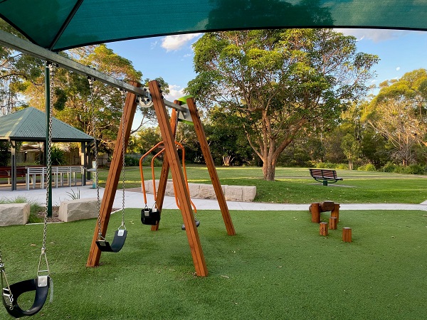 View of swing set and leafy reserve