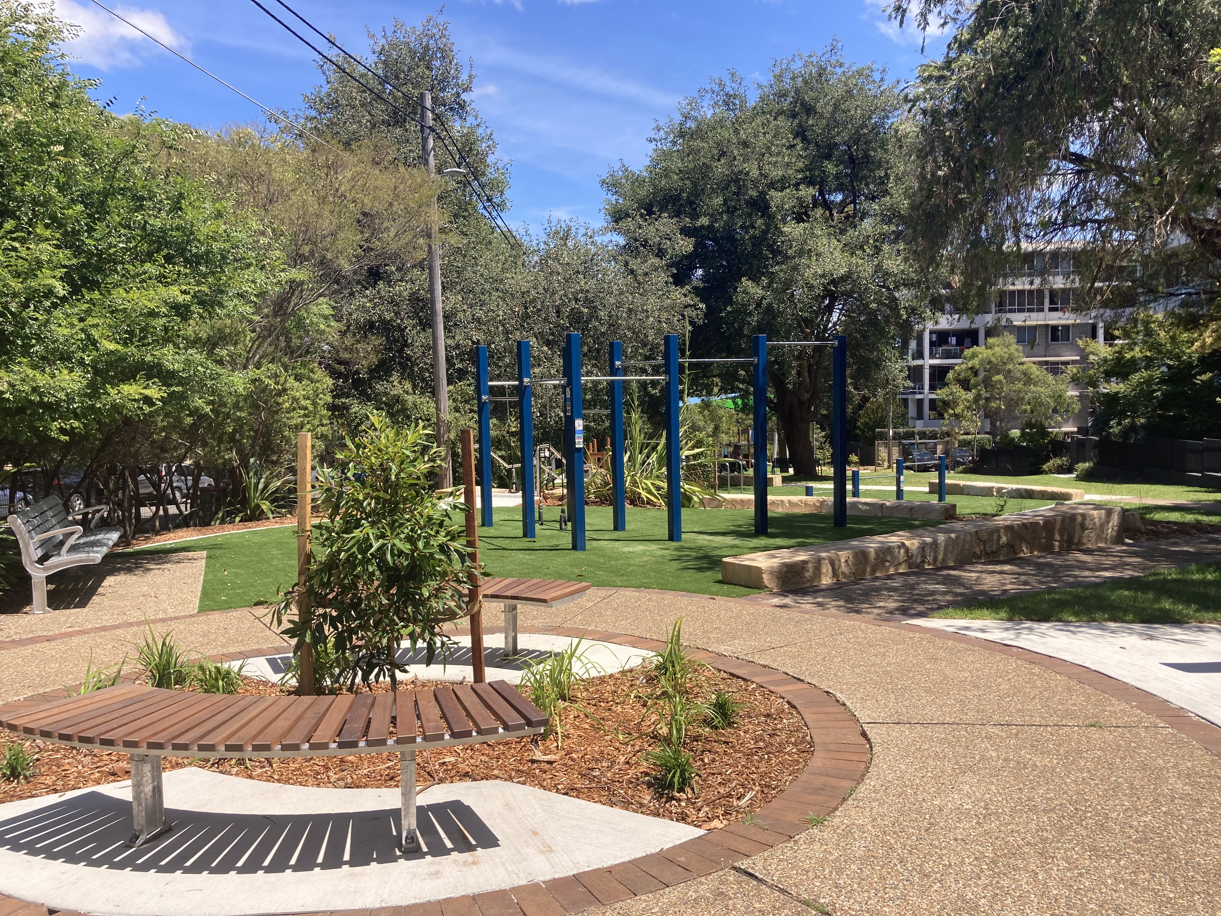 Shady park with fitness equipment and seating