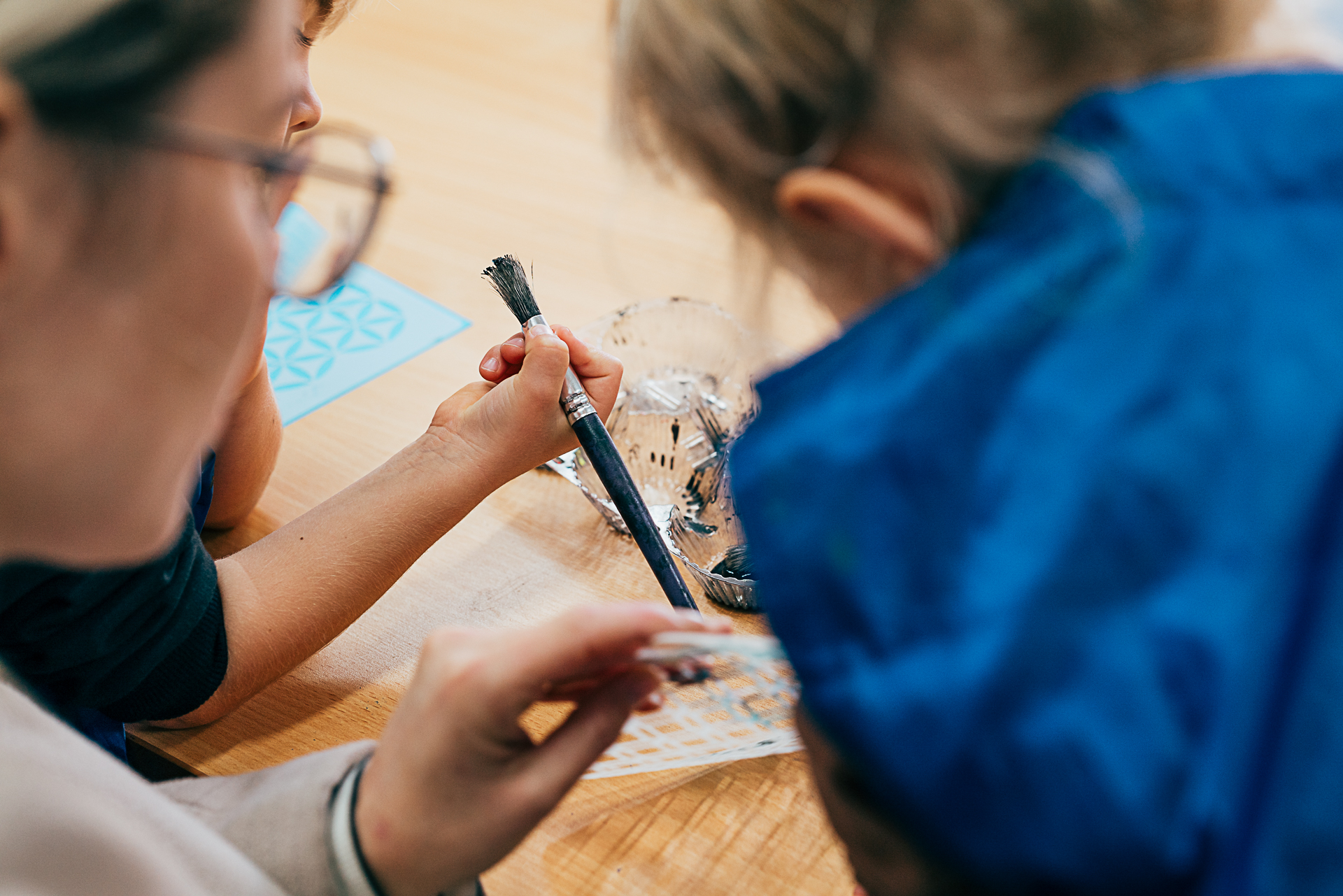 Looking over the shoulder of a mother and her two children making art together.