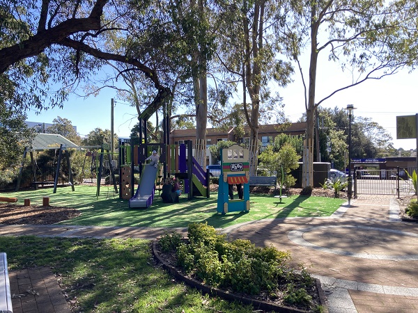 Park with playground, garden beds and boundary fence
