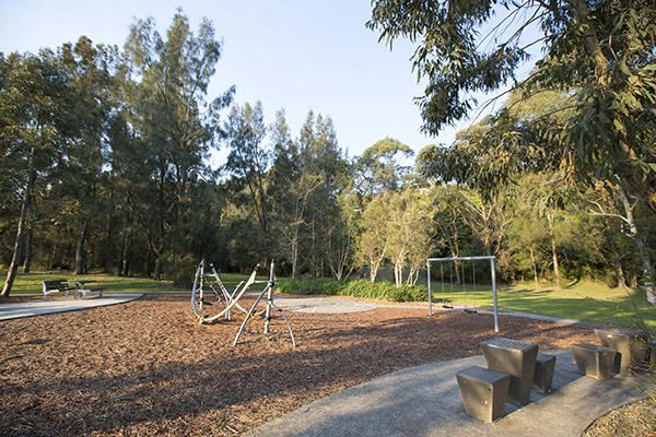Playground with slides, climber and seats on bark softfall