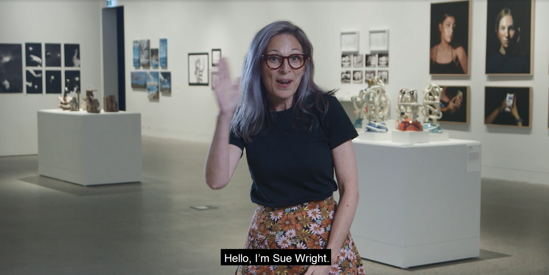 Woman with purple hair standing in art gallery. She is signing 