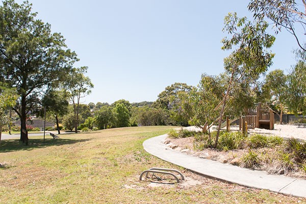 Grassy open space with trees and sandy playground