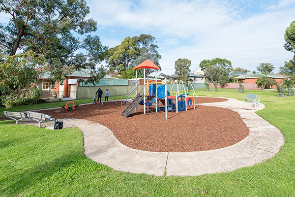 Playground with seating and scooter track in grassy park