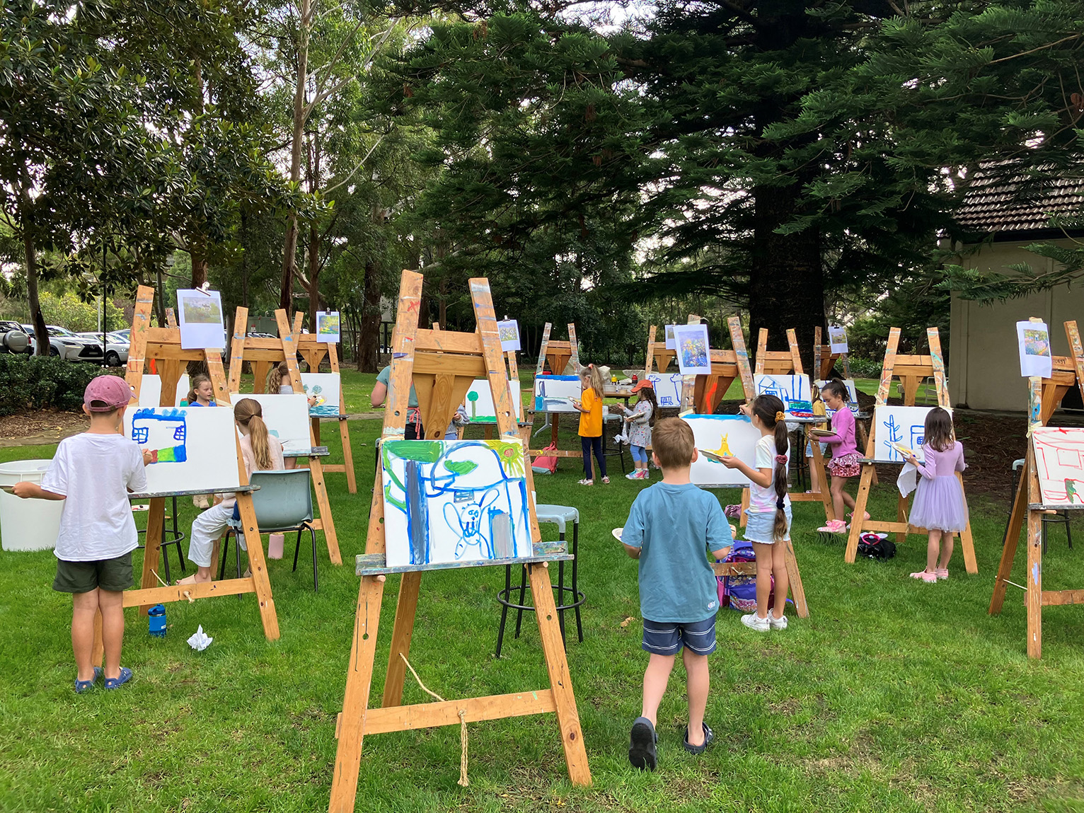 A large group of children painting at easels in the Hazelhurst gardens.