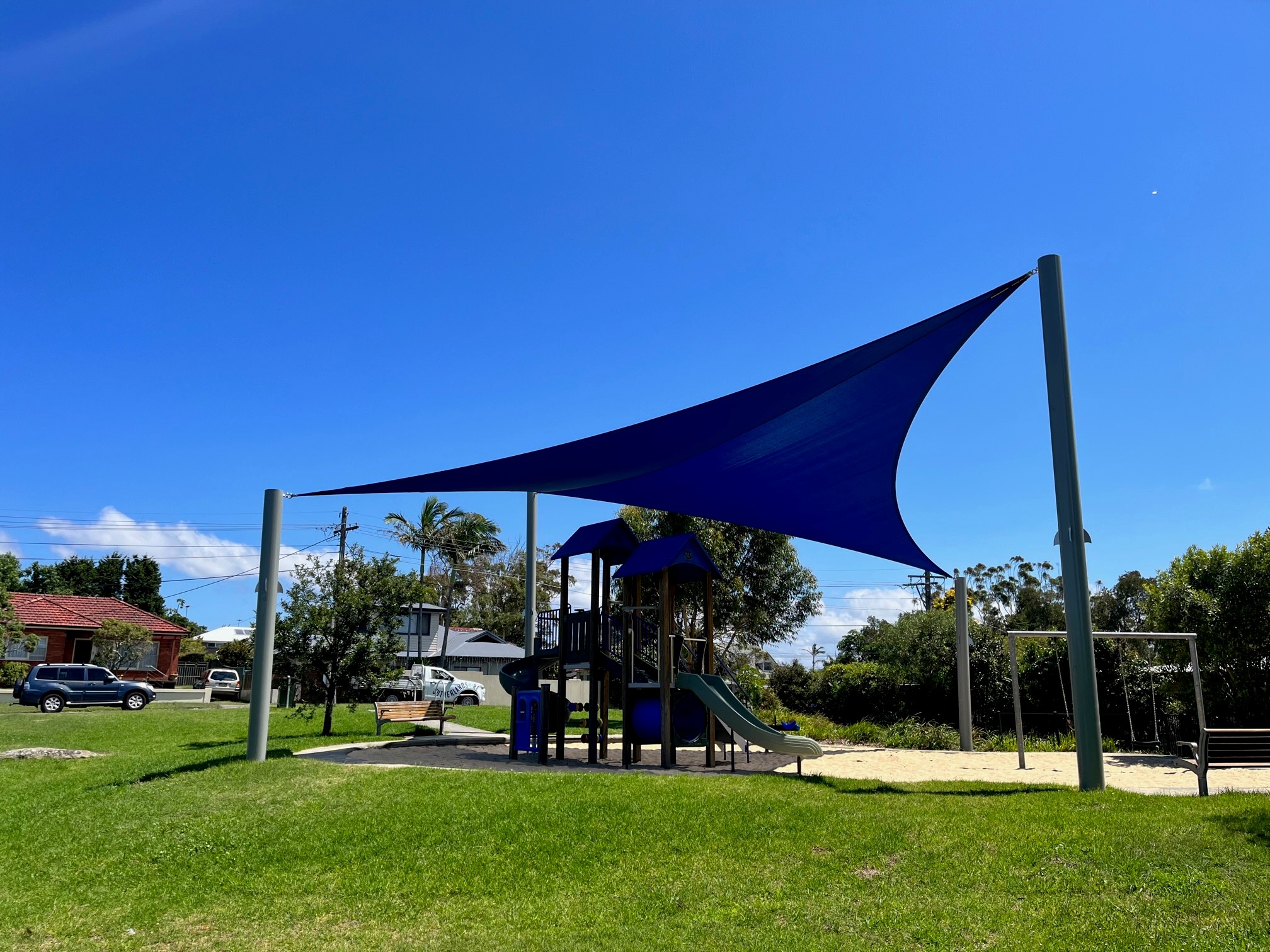 Shaded playground with tower, slides and swings