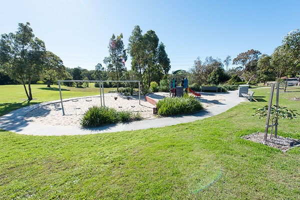 Sunny grassed reserve with play equipment and mature trees