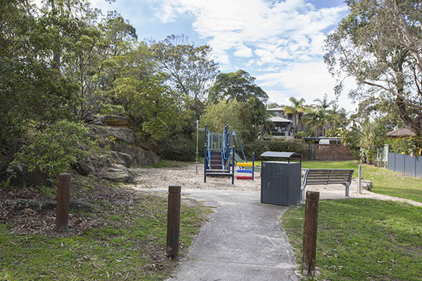 Sandy playground with trees and seat