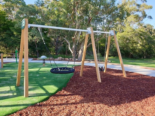 Basket and toddler swings in leafy reserve