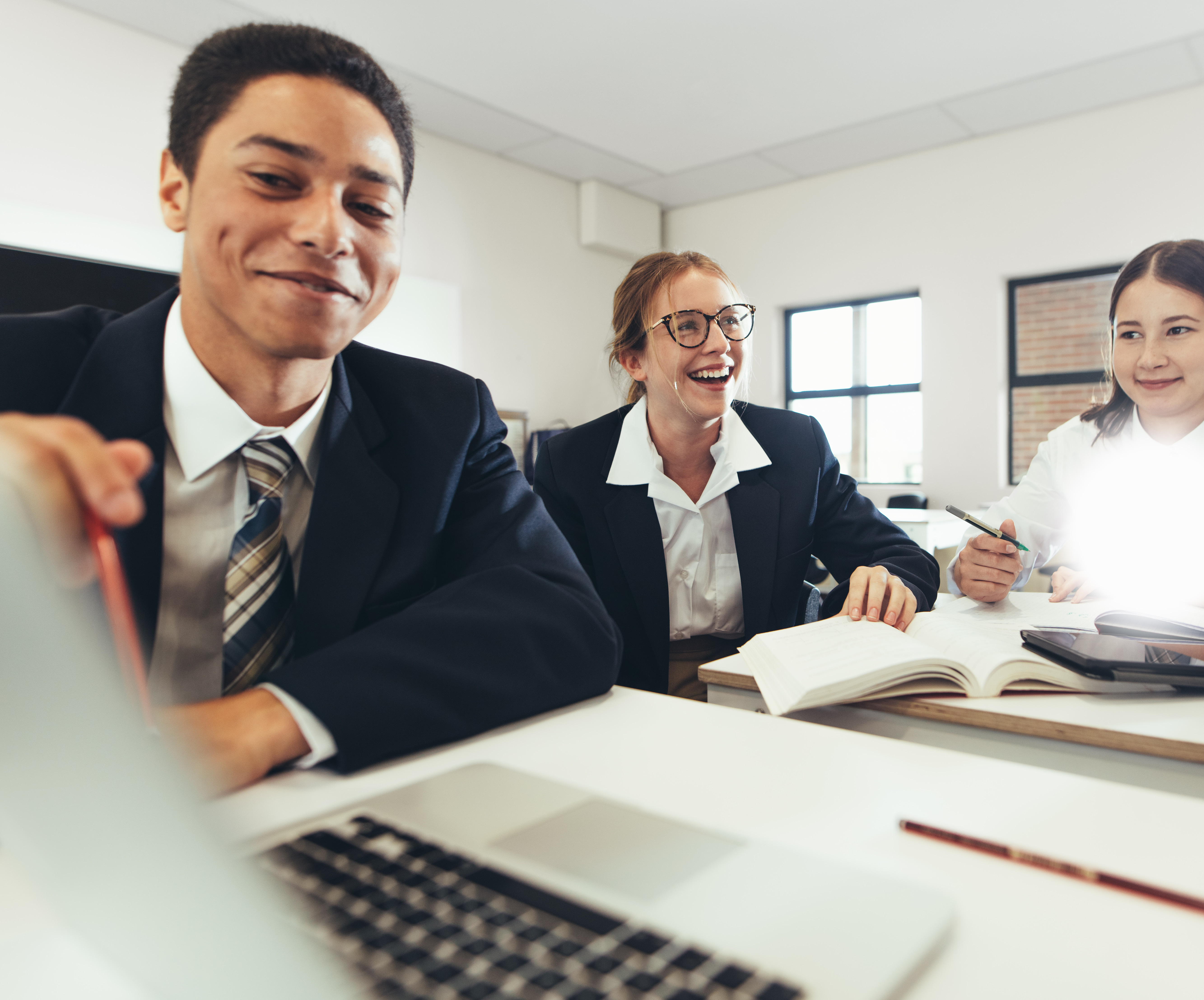 high school students smile at laptop in class